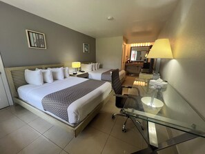 A hotel room with two beds, a desk with a chair, a mirror, and a small kitchenette. - Garden Inn Homestead/Everglades/Gateway to Keys (Homestead)