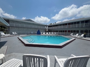 A pool area with lounge chairs and a blue cover over the pool.
