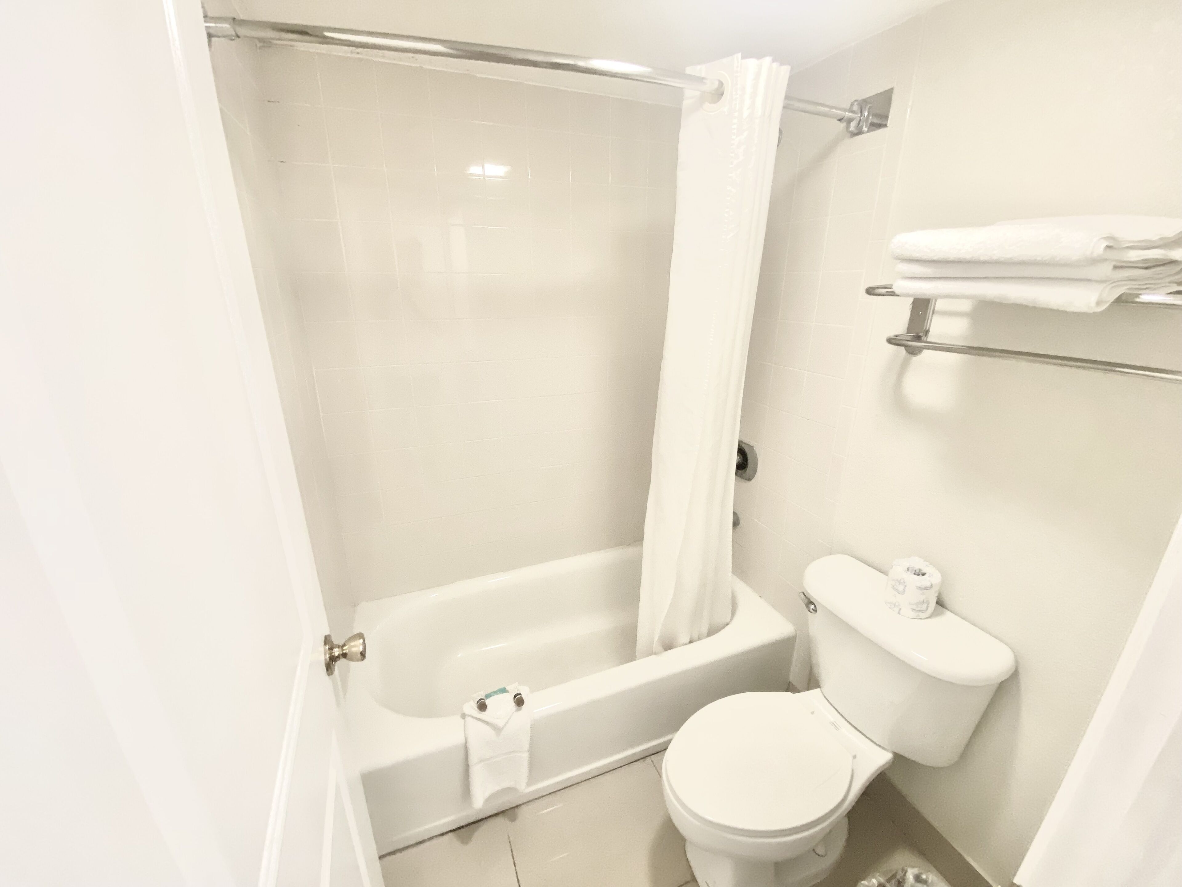 A bathroom with a bathtub, toilet, and a towel rack.