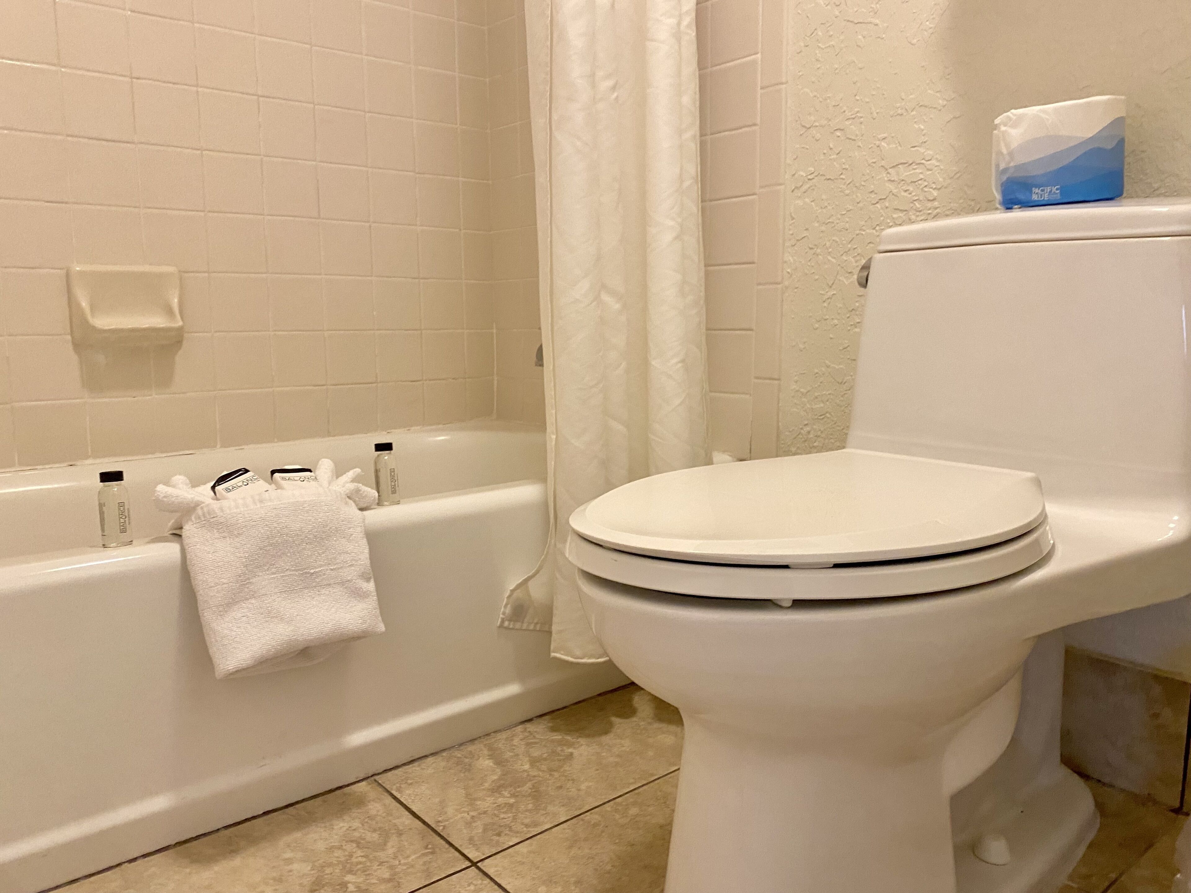 A bathroom with a bathtub, toilet, and a towel hanging on the wall.