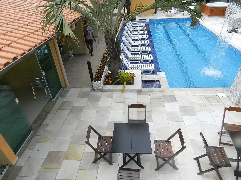 Area piscina con lettini e un tavolo, circondata da palme e un patio piastrellato.