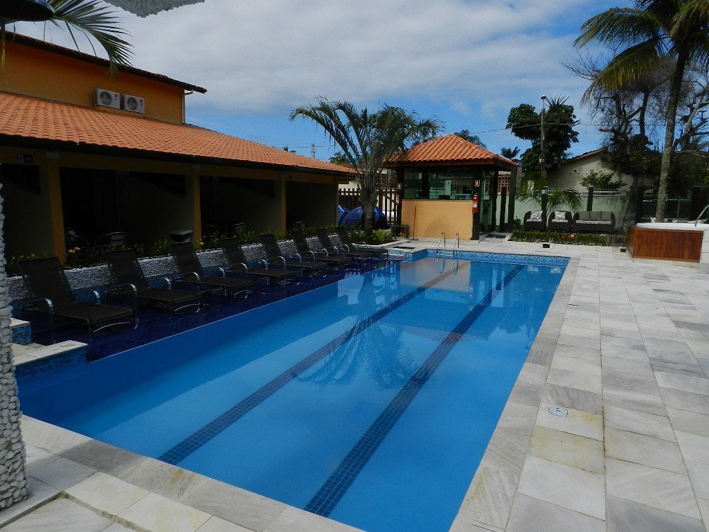 A swimming pool with lounge chairs, a covered seating area, and a small pavilion.