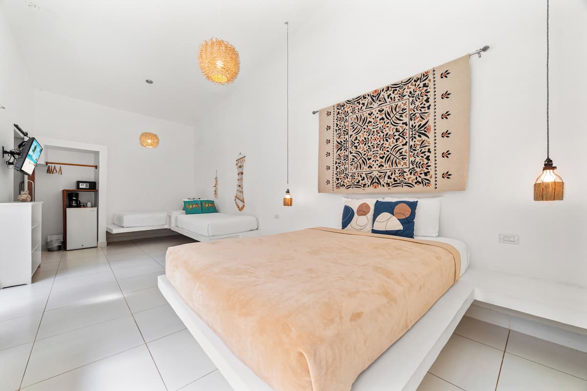 Een moderne slaapkamer met een groot bed, een zithoekje en een wandtapijt.