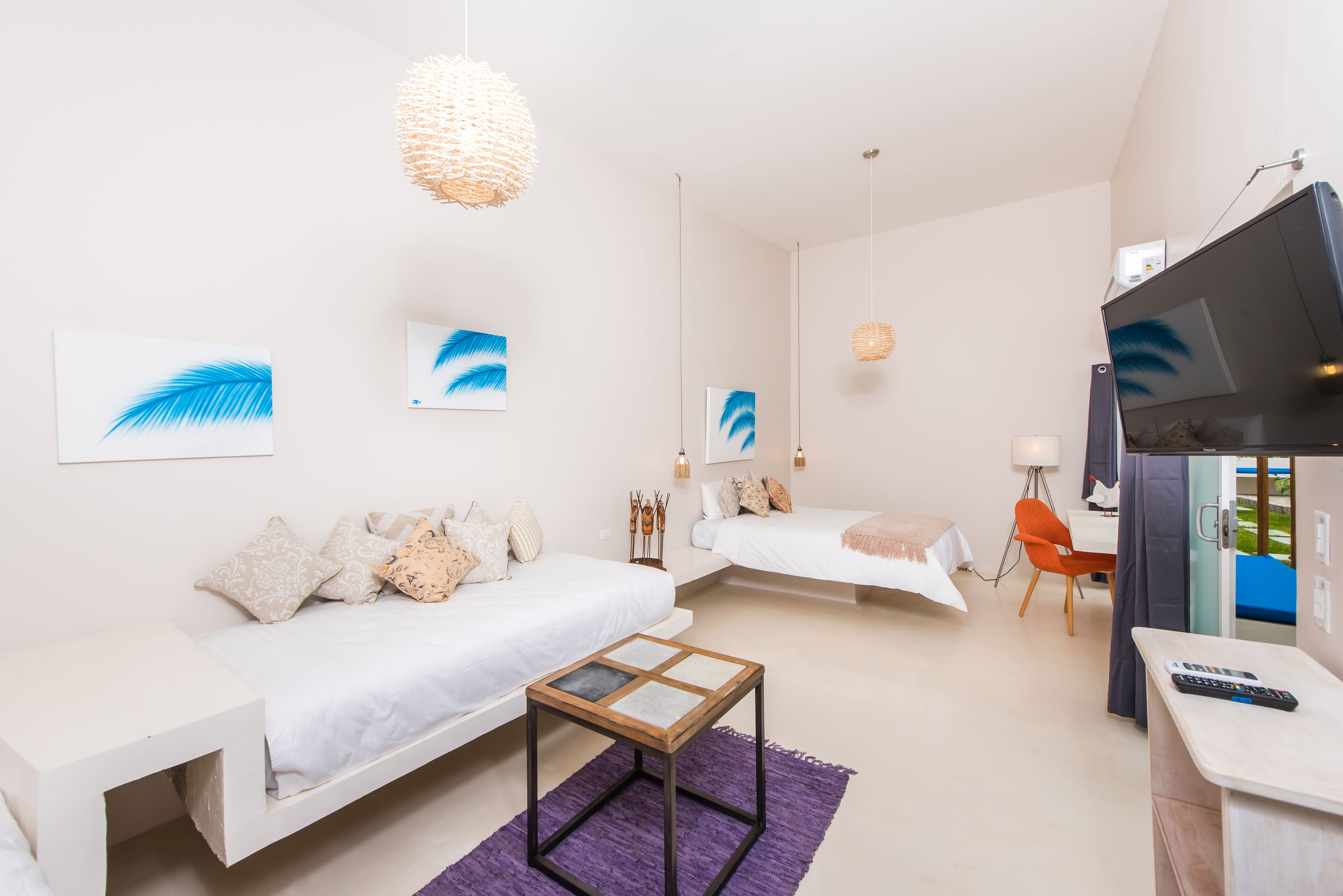 Una habitación de hotel moderna con dos camas, una mesita, un televisor y obras de arte en las paredes.
