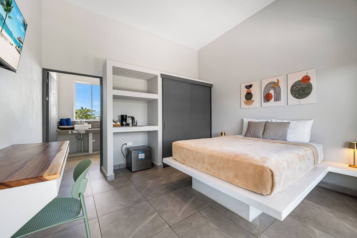 Een moderne slaapkamer met een bed, een bureau en een kitchenette.