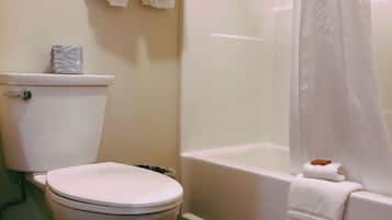 Une salle de bain équipée de toilettes, d’une baignoire et d’un rideau de douche.