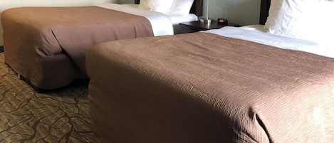 A hotel room with two beds, a nightstand, and a patterned carpet.