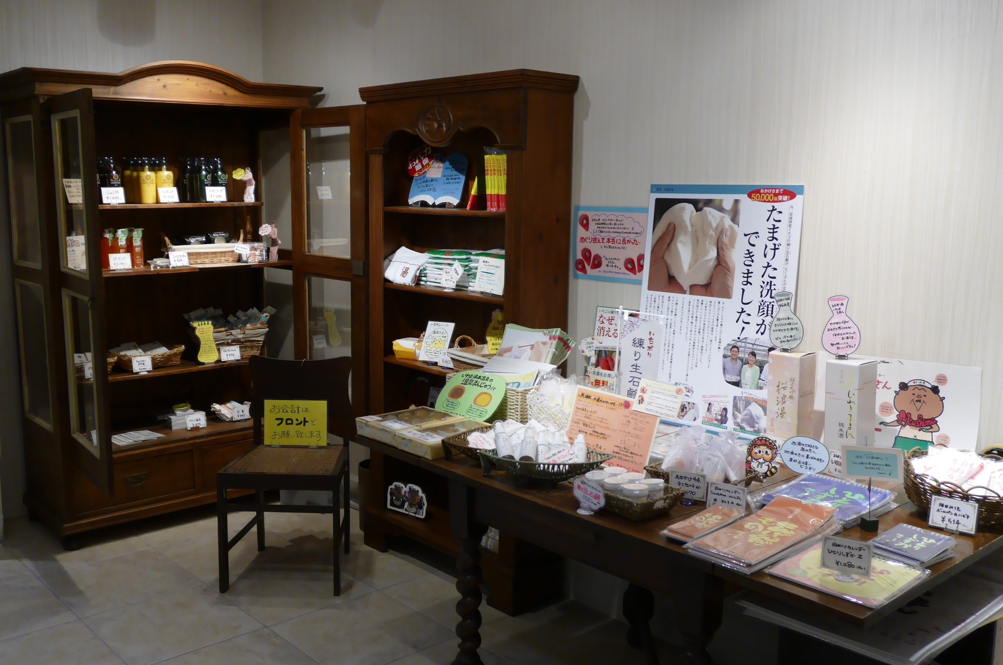 A display of various products on a table with price tags, surrounded by wooden shelves with more items.