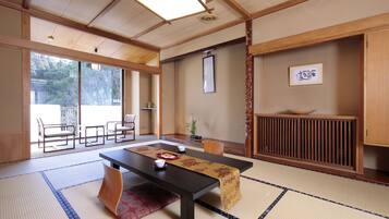 A traditional Japanese room with tatami flooring, a low table with a table runner, a wooden cabinet, and a sliding door leading to an outdoor area.