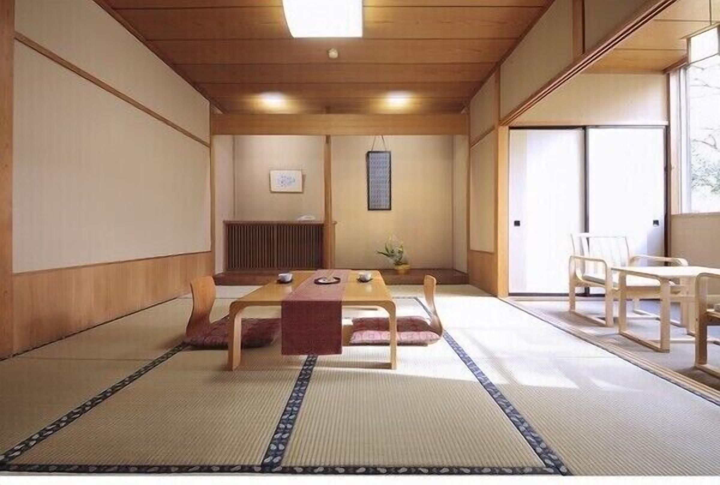 Una habitación japonesa tradicional con suelo de tatami, una mesa baja y puertas correderas.