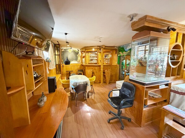 A cozy, well-lit room with wooden furniture, a glass display case, and a small table with chairs. - Hotel Inka King - Hostel (Ollantaytambo)