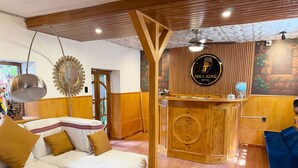A hotel lobby with a reception desk, a sofa, a coffee table, and a decorative wall. - Hotel Inka King - Hostel (Ollantaytambo)