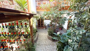 A courtyard with potted plants, a wooden pergola, and a tiled floor. - Hotel Inka King - Hostel (Ollantaytambo)