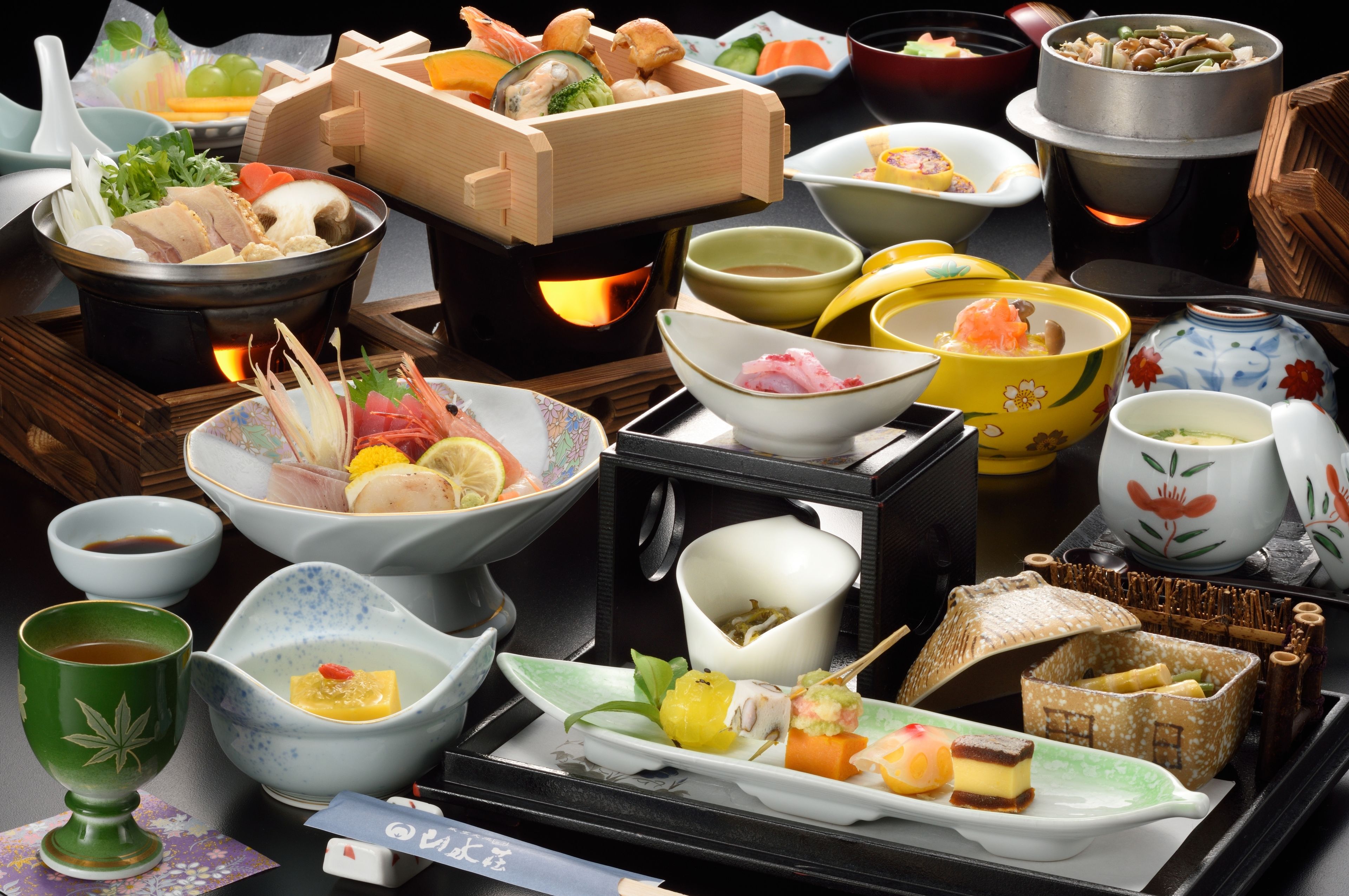 A variety of Japanese dishes and traditional tea set on a tray.