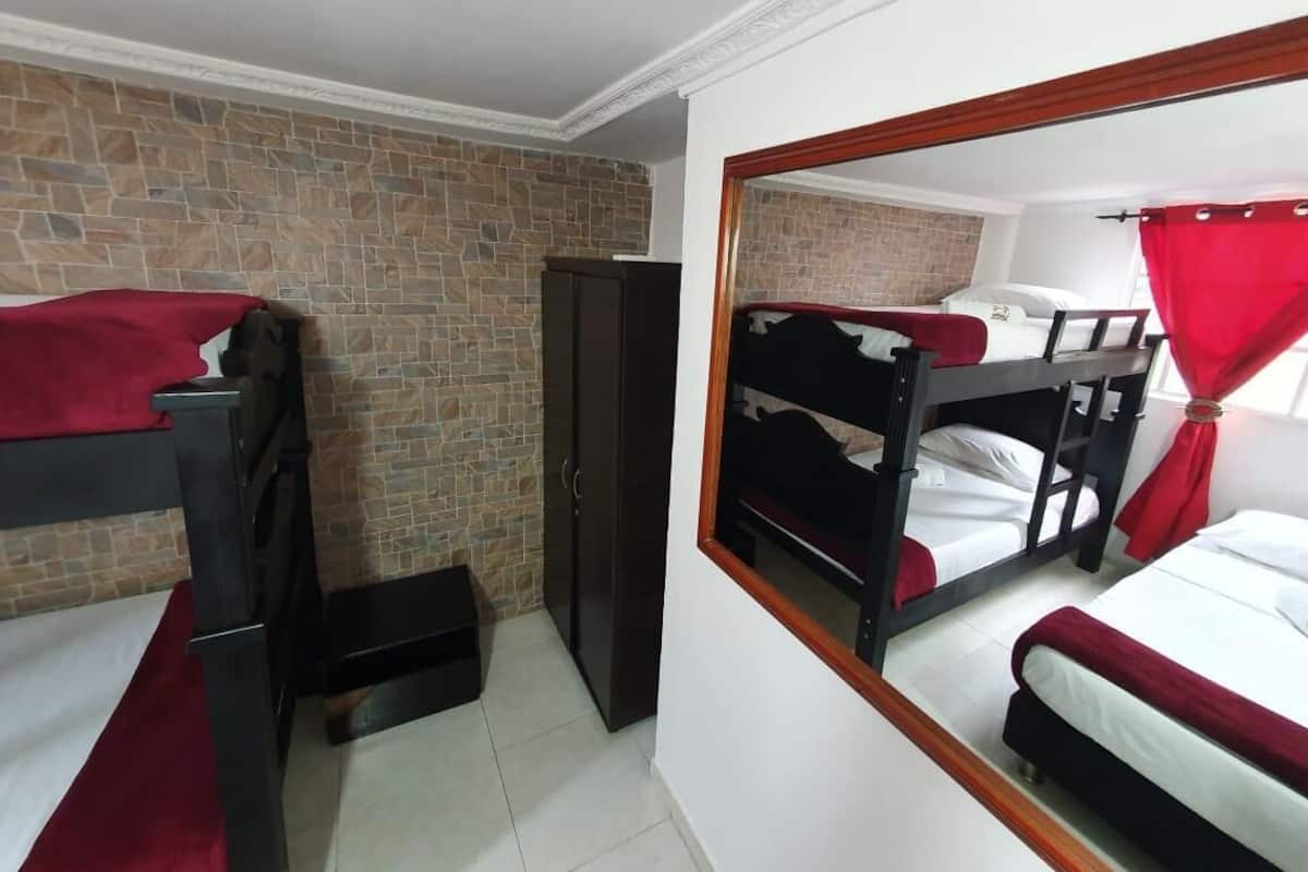 A room with bunk beds, a wardrobe, and a mirror reflecting the room.
