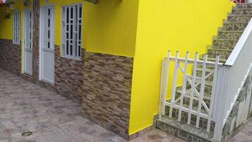 Un edificio con fachada amarilla, una escalera de piedra y una verja blanca.
