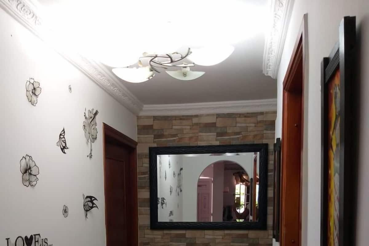 A hallway with a stone wall, a mirror, and a door.