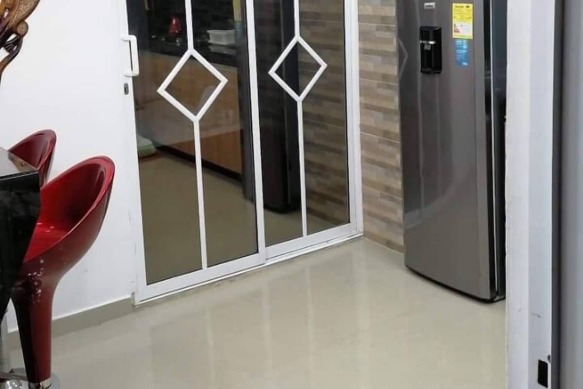 A modern kitchen with a stainless steel refrigerator, a wooden cabinet, and a glass door with diamond-shaped cutouts.