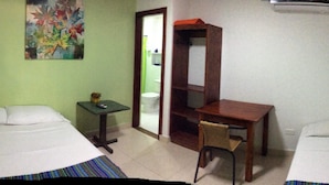 A hotel room with two beds, a desk, a chair, a small table, and a painting on the wall. - La Posada de Lulu (San Andrés)