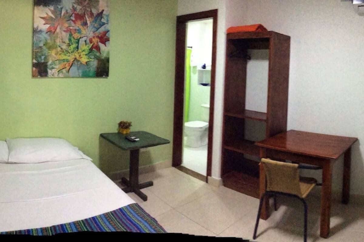 Une chambre d’hôtel avec deux lits, un bureau, une chaise, une petite table et un tableau au mur.