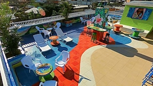 A pool area with lounge chairs and tables, surrounded by a white fence and greenery. - La Posada de Lulu (San Andrés)