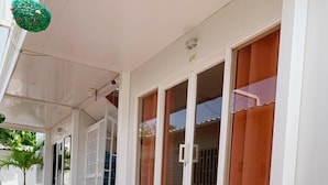 Un espacio exterior cubierto con suelo de baldosas, grandes puertas correderas de vidrio y una planta en maceta.