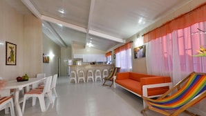 Un salón amplio con una mesa de comedor, sillas, sofá y una hamaca.