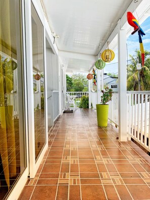 A covered balcony with tiled flooring, white railings, and a potted plant. - Tropical Coral (San Andrés)