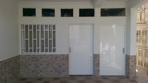 A building facade with a white exterior, a brick lower section, and a metal gate on the right. - Hospedaje Solymar I Sarie Bay (San Andrés)