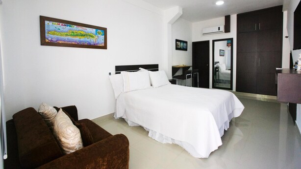 A hotel room with a bed, a brown sofa, a map on the wall, and a wardrobe. - Hospedaje Solymar I Sarie Bay (San Andrés)