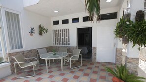 A covered patio with a tiled floor, a round table, and four chairs. - Hospedaje Solymar I Sarie Bay (San Andrés)