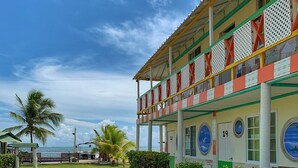 A two-story building with a covered walkway and a view of the ocean. - Posada Donde Pilo Avila (San Andrés)