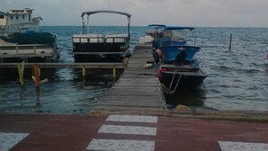 A pier with boats docked, a clear sky, and calm water. - Posada Donde Pilo Avila (San Andrés)