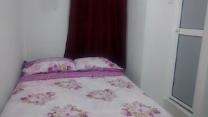 A small, neatly made bed with floral bedding in a room with white walls and a dark curtain. - Posada Estrella del Mar (Isla de San Andres)