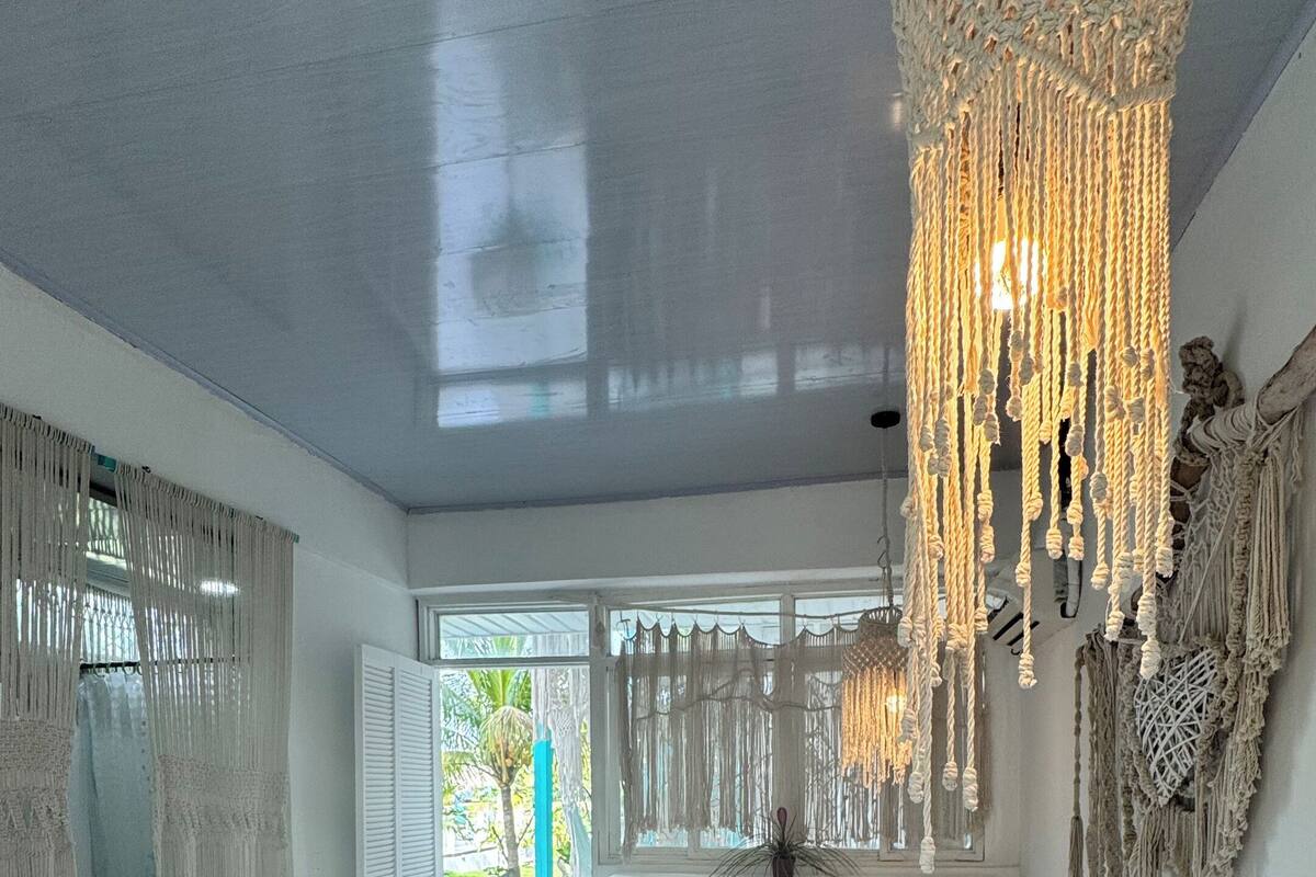 Une chambre spacieuse avec un grand lit, des décorations murales en macramé et une vue sur la verdure.