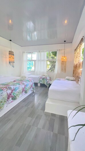Une chambre d’hôtel avec deux lits, une grande fenêtre et un luminaire au plafond.