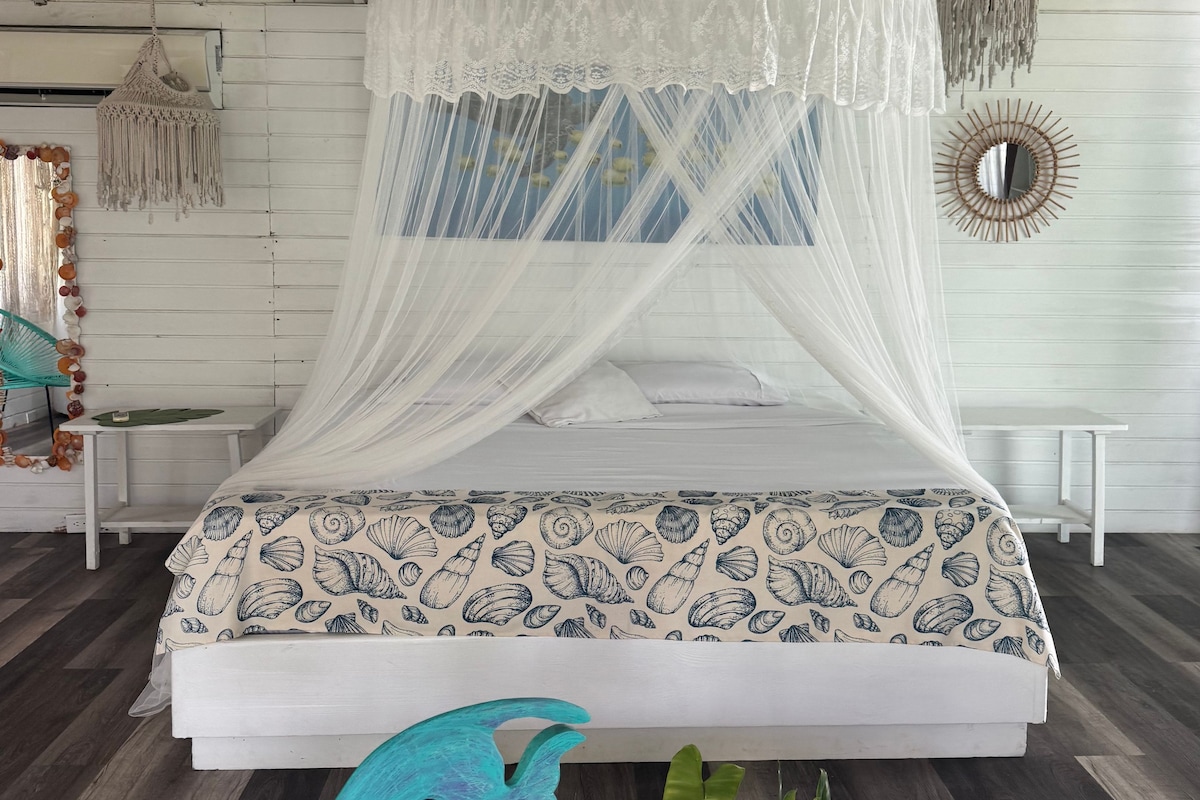 A bed with a white canopy and a seashell patterned bedspread.