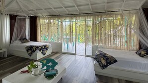 Una habitación amplia con techo alto, ventilador de techo, cama, sofá y mesa de centro.