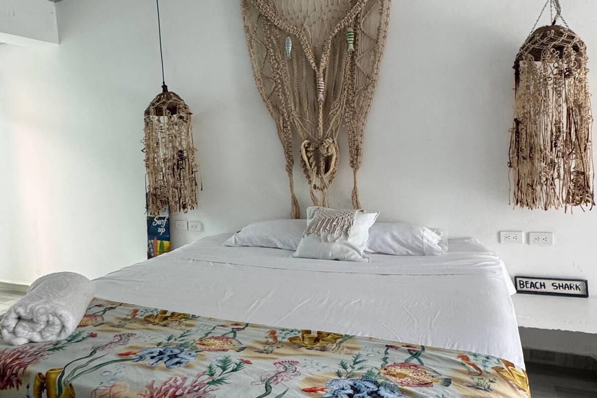 Une chambre avec un lit, une décoration murale en macramé et deux lampes en macramé.