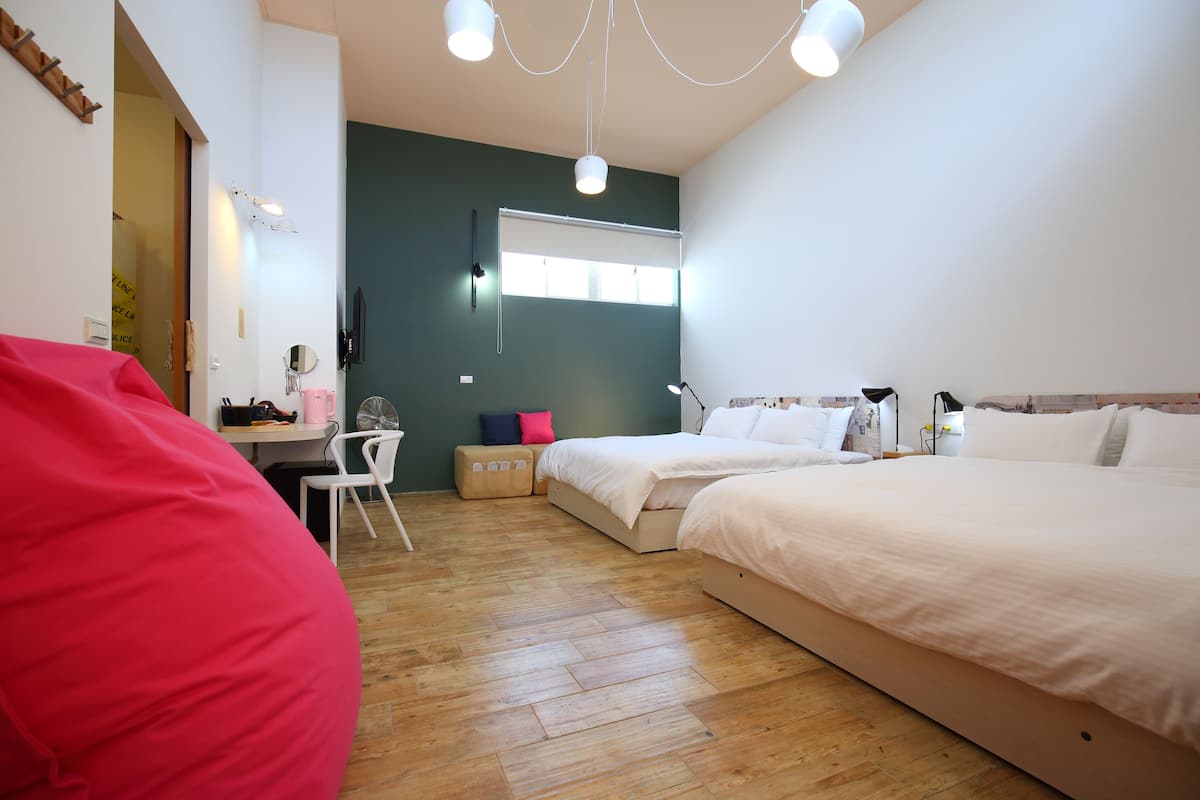 A bedroom with two beds, a desk, a chair, and a bean bag.