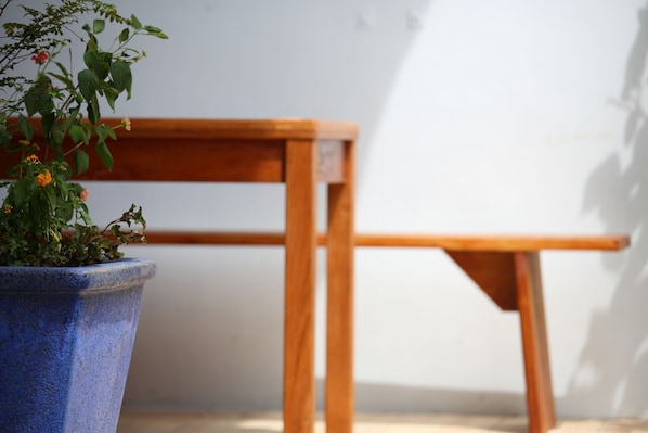 A wooden chair and a blue pot with plants against a white wall. - Ttdropin B&B (Taitung)