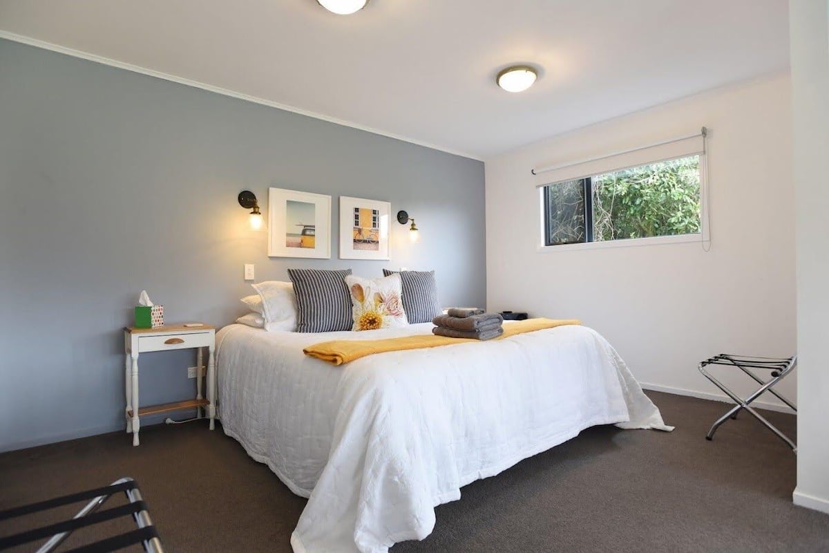 A neatly arranged bedroom with a bed, bedside table, and a window with a view of greenery.