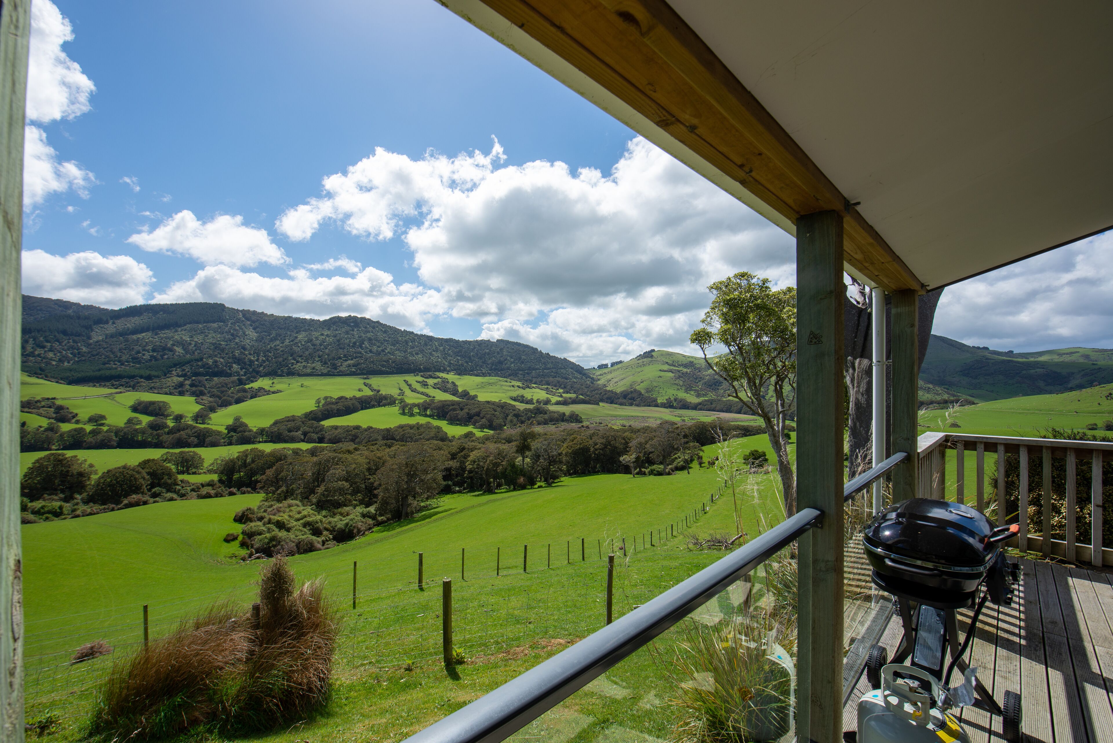 A balcony with a view of rolling green hills and a clear sky.