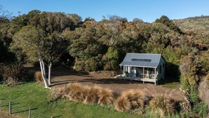 A single-story house with a sloped roof, surrounded by dense forest. - Mohua Park - Catlins Eco Accommodation (Tawanui)