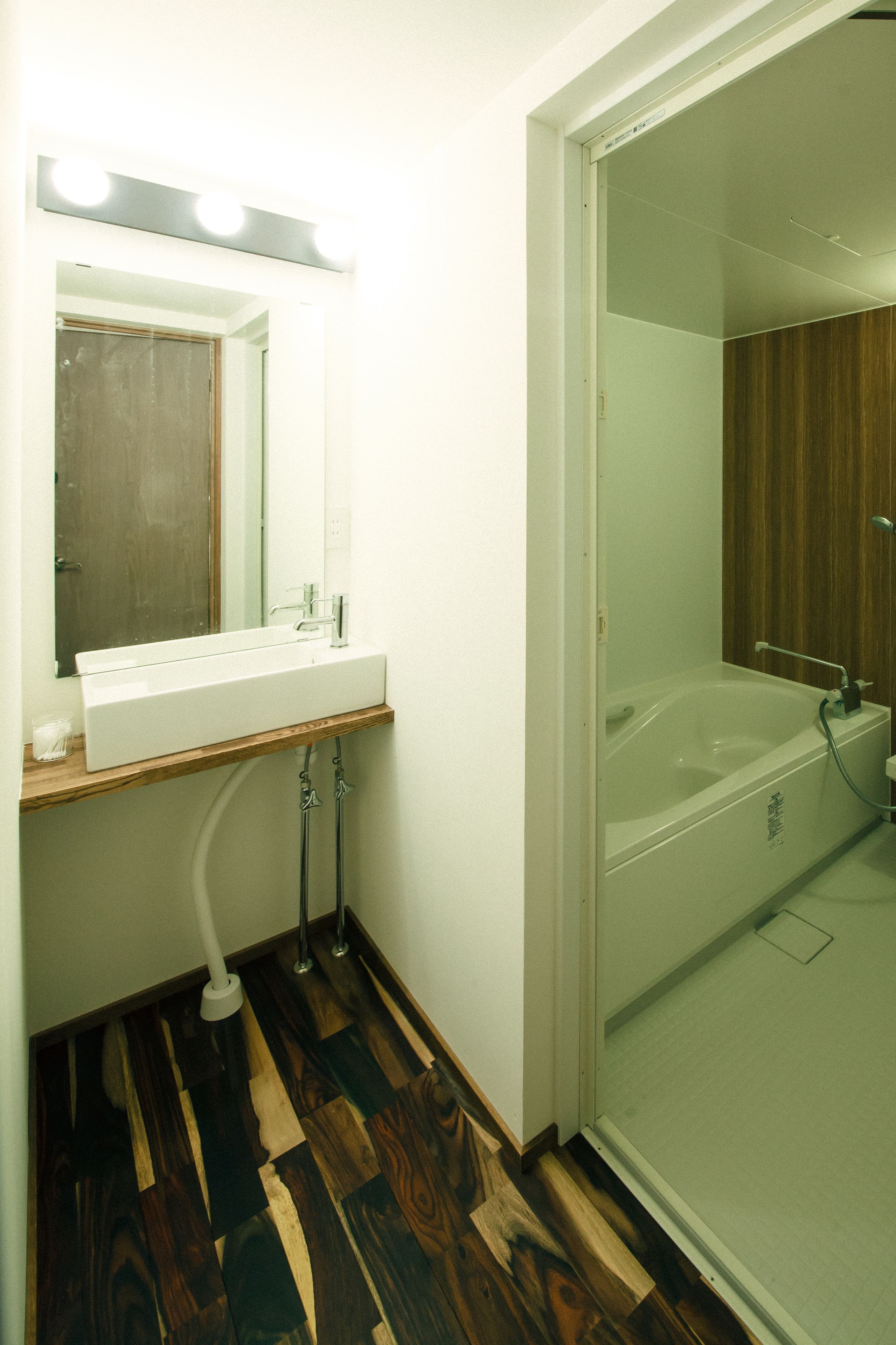 A bathroom with a wooden vanity, a sink, a mirror with lights, and a glass-enclosed shower area.