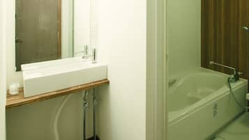 A bathroom with a wooden vanity, a sink, a mirror with lights, and a glass-enclosed shower area.
