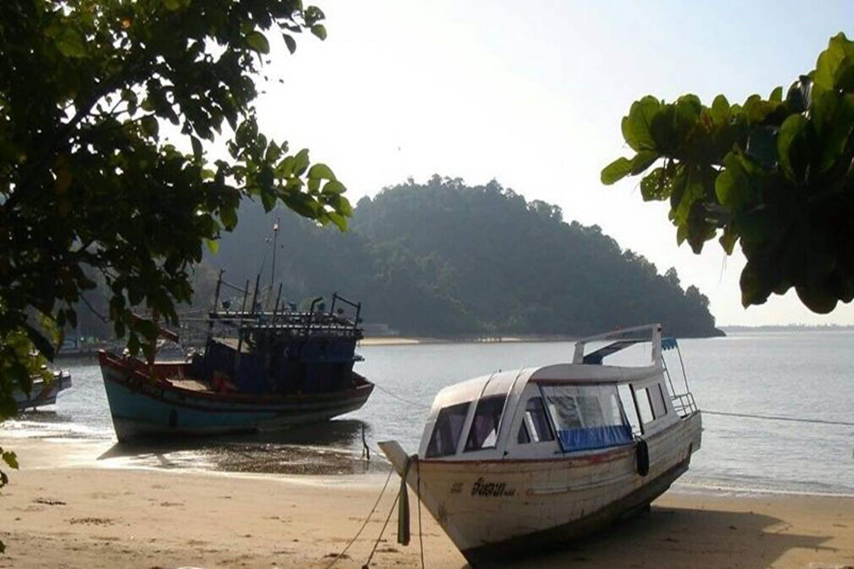 Un bateau était amarré sur une plage de sable, avec une île boisée en arrière-plan.