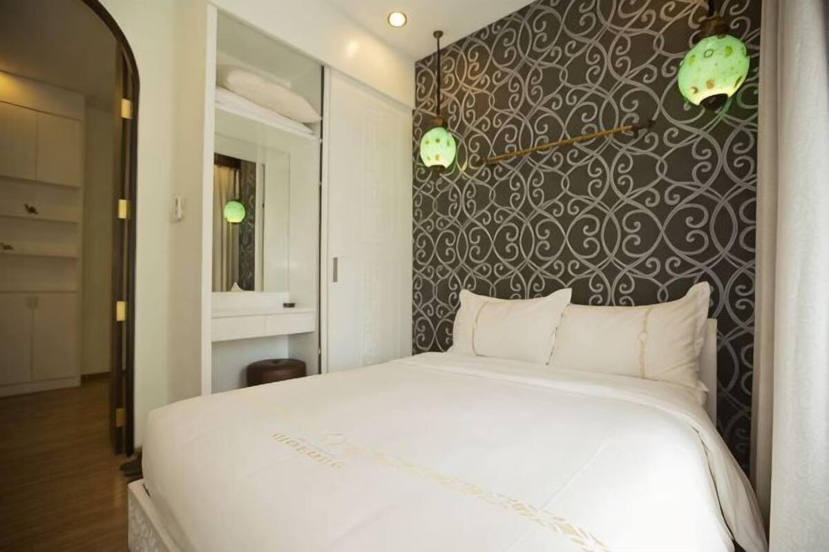 A bedroom with a large bed, a mirror, and patterned wallpaper.