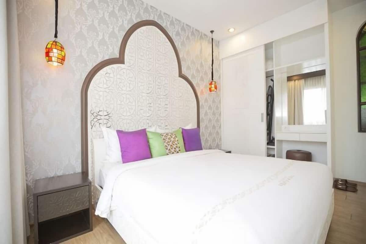 A bedroom with a large bed, a headboard with a decorative pattern, and a nightstand.