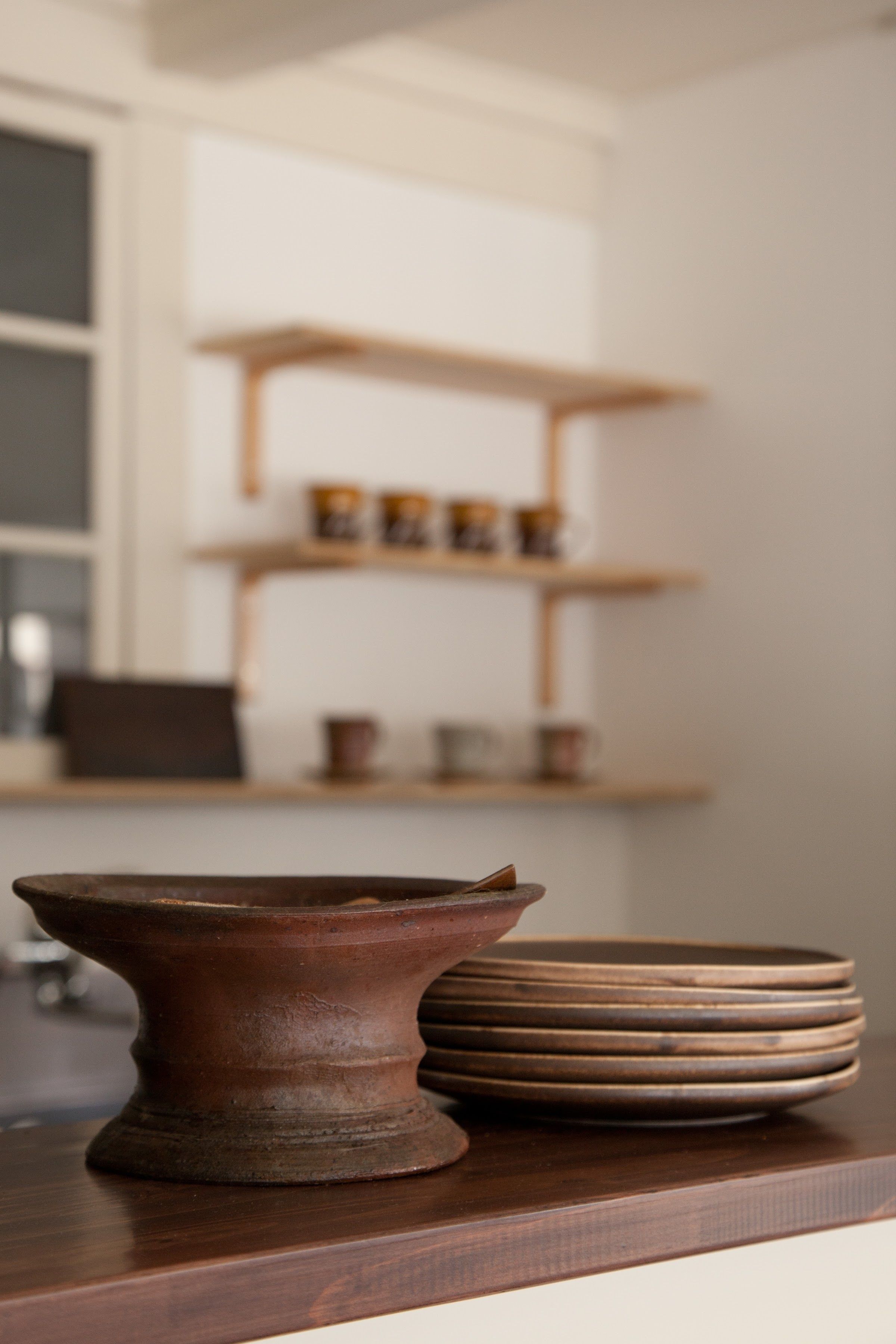 Un comptoir de cuisine orné d’un bol en poterie rustique et de piles d’assiettes.